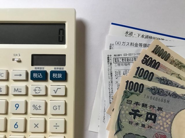 電気料金の払い込み通知書と電卓と紙幣